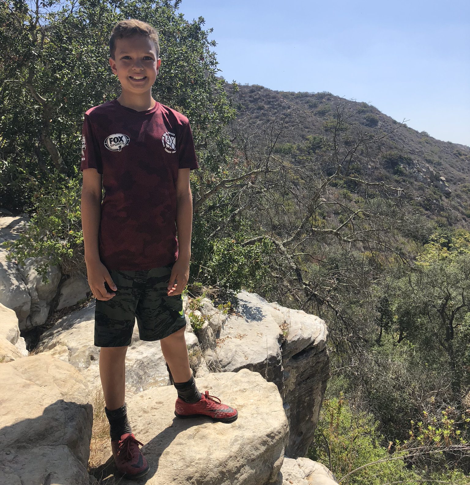 Young Boy on a hike, on top of rocky crest in canyon