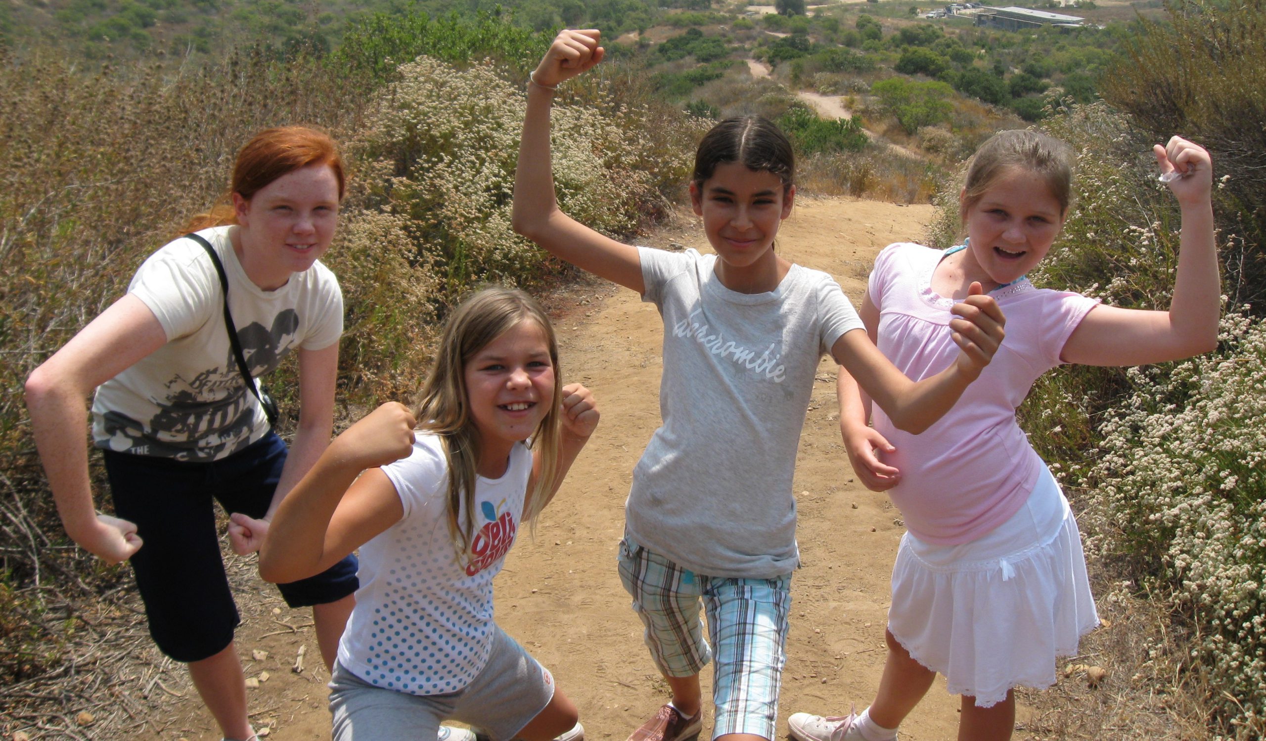 four young girls on a hike in the canyon showing their muscles