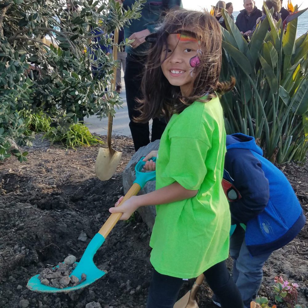 Young girl with shovel in planter