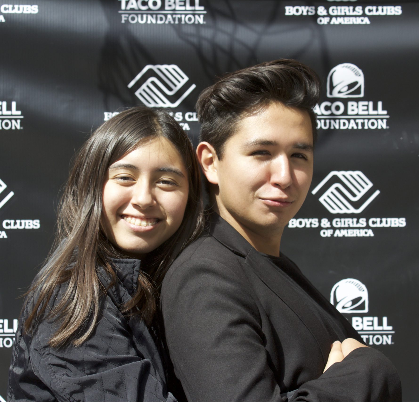 boy and girl in front of event logo backdrop