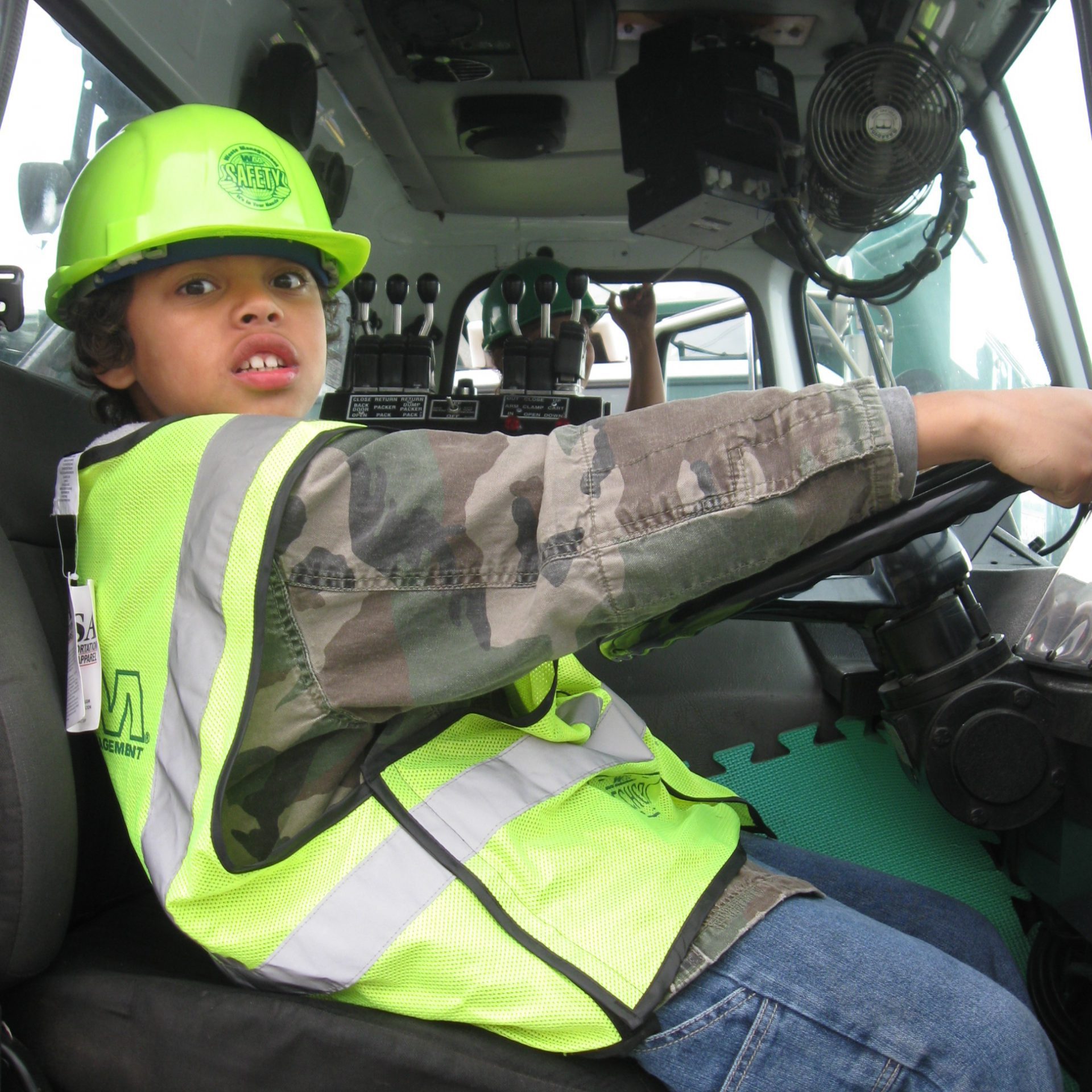 young boy in drivers seat of Waste Management truck