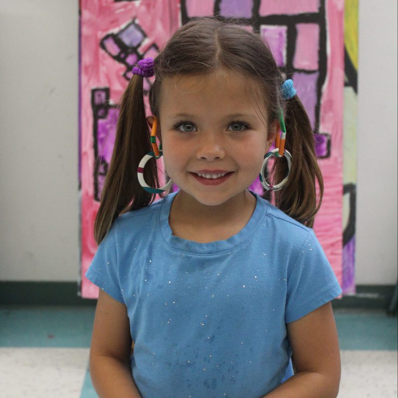 young girl in blue shirt with over the ear rings