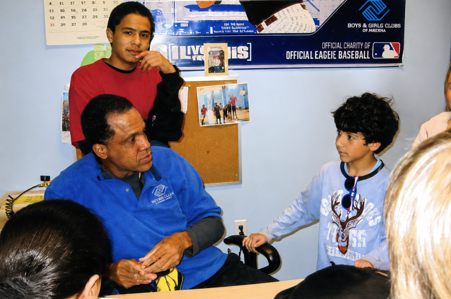 Hans Laroche (in blue) speaks with children at the Boys & Girls Club while Erik Vasquez (in red) stands nearby.