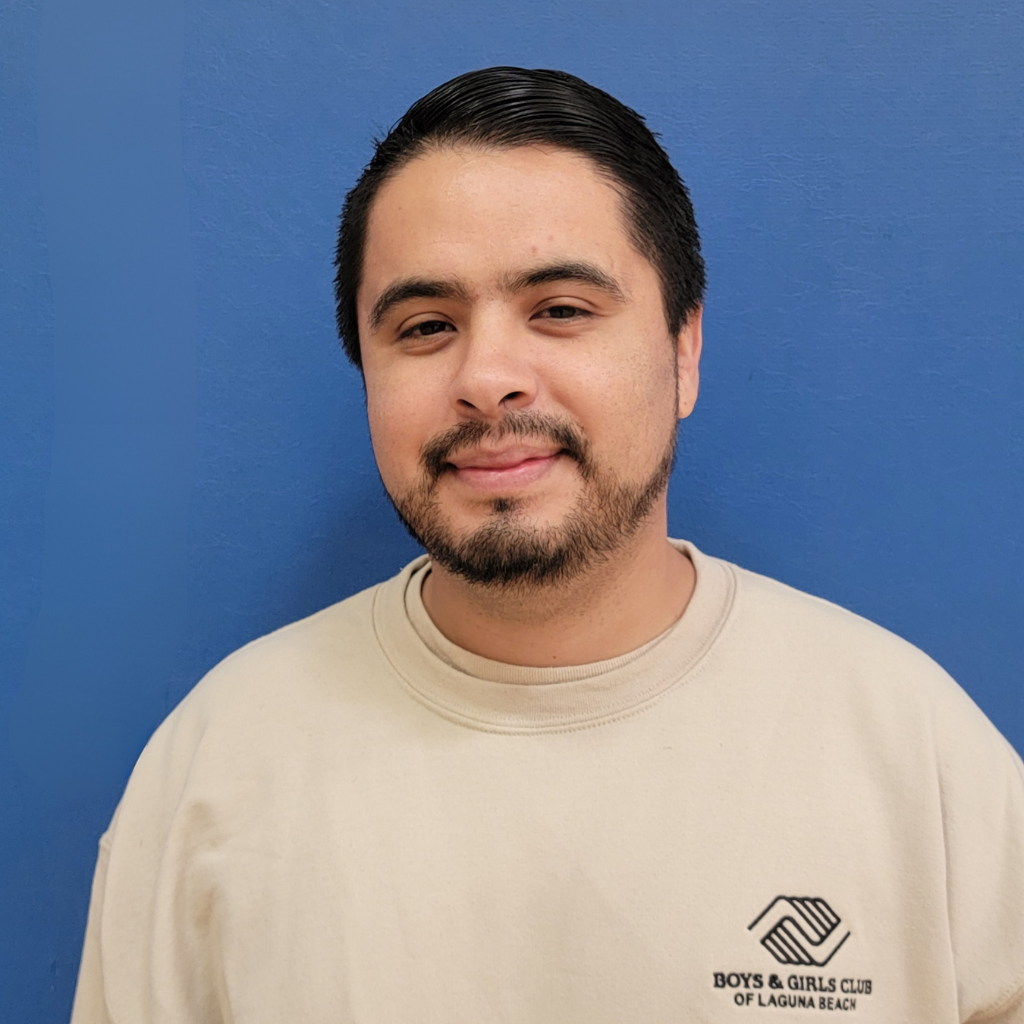 Erik Vasquez, Sports and Recreation Director at Boys and Girls Club of Laguna Beach, smiling in front of blue wall